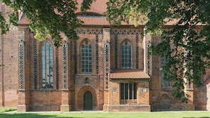 A brick building with arched windows and a central door, surrounded by a well-maintained lawn. - Apartment in the commandery near the Elbe (Werben)