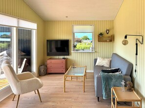 Un salon avec un téléviseur, un canapé, un fauteuil et une petite table.