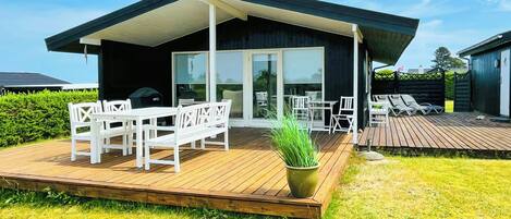 A modern house with a deck, outdoor seating, and a large sliding glass door.