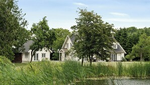 A row of white houses with gabled roofs, surrounded by trees and a body of water. - Guest house by lake and forest (Nakskov)