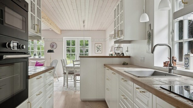 A kitchen with white cabinets, a wooden countertop, and a built-in oven. - Guest house by lake and forest (Nakskov)