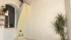 A spa area with a brick arch, a white wall, a small pool, and a plant. - Nala Narty Nubian house and organic farm (Aswan)
