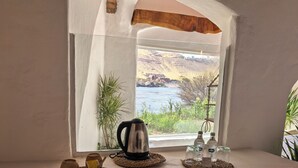 A room with a window overlooking a river, a table with a kettle, and two bottles. - Nala Narty Nubian house and organic farm (Aswan)