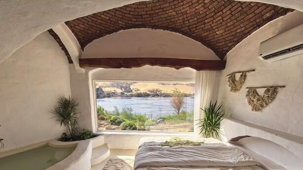 A room with a view of a river, a bathtub, and a bed with pillows. - Nala Narty Nubian house and organic farm (Aswan)