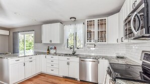 Una cocina moderna con armarios blancos, lavavajillas de acero inoxidable y estufa negra.