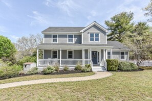 A two-story house with a front porch, a small attached garage, and a well-maintained lawn. - Corn Hill Ranch - East Falmouth (Falmouth)