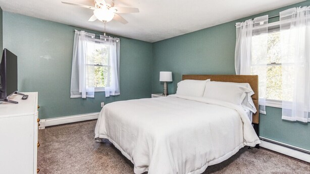 Un dormitorio con cama, escritorio, lámpara y ventilador de techo.