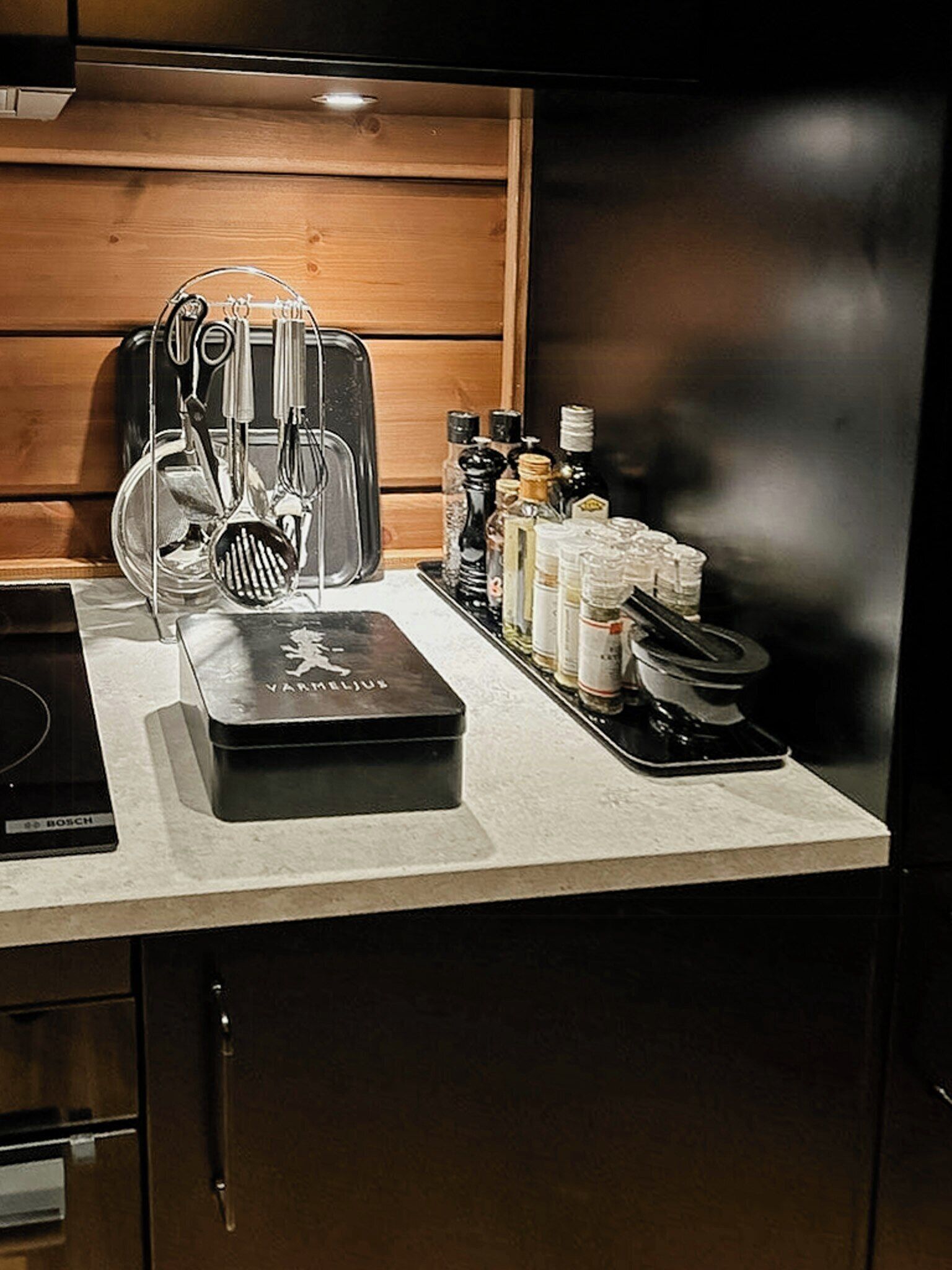 Een keukenblad met een Bosch inductiekookplaat, een VAMILJUS koffiezetapparaat en verschillende keukengerei en kruiden.