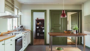 Una cocina con encimera de madera, una lámpara colgante roja y una puerta verde.
