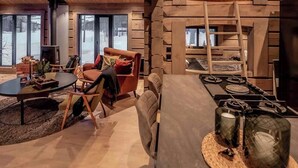 A log cabin interior with a fireplace, a dining table, and a cozy seating area. - Cabin with great fishing at Trysilfjellet (Jordet)