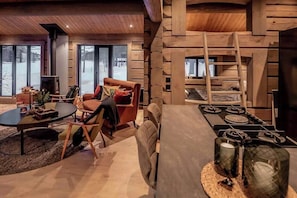 A log cabin interior with a fireplace, a dining table, and a cozy seating area. - Cabin with great fishing at Trysilfjellet (Jordet)