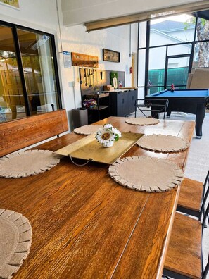 Ein Essbereich mit einem Holztisch, beigen Platzsets und einer Blumenarragemnt.