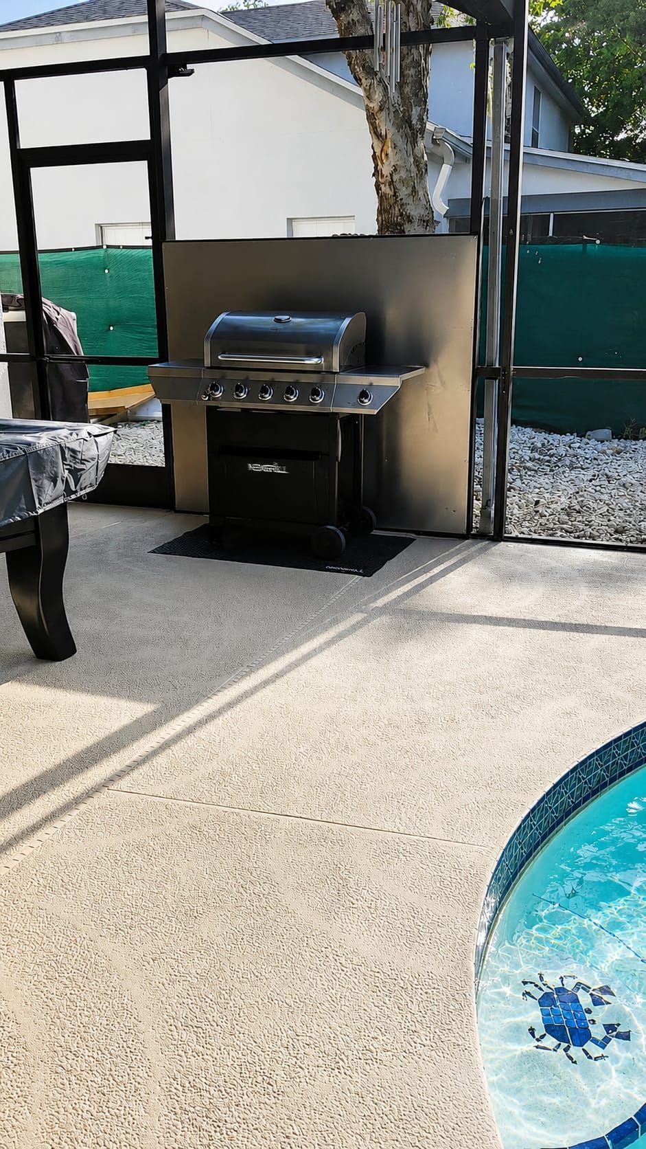 An outdoor patio with a grill, a pool with a crab design, and a covered seating area.