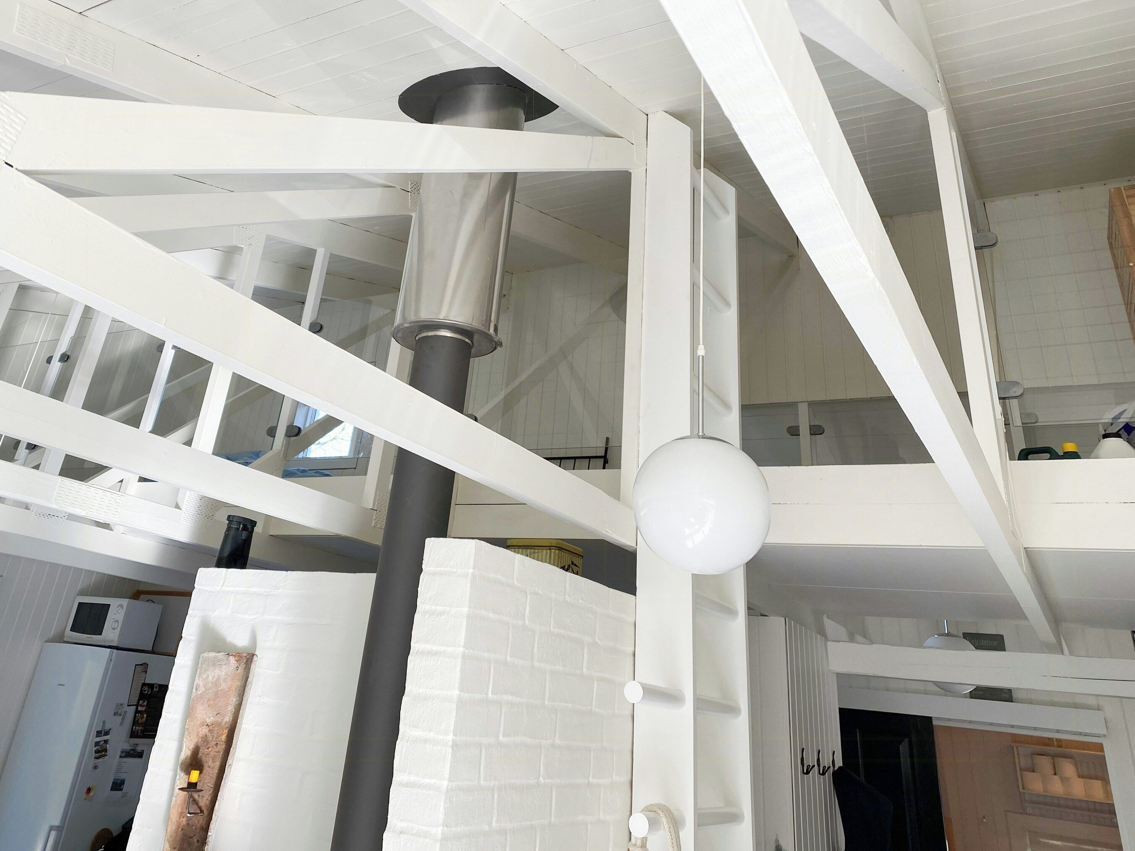 A modern interior with exposed structural beams, a central column, and a hanging light fixture.