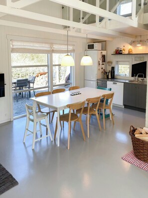 A modern kitchen with white cabinetry, a dining area with a white table and wooden chairs, and a large window providing natural light. - Personality in architect home near Spøttrup (Spøttrup)