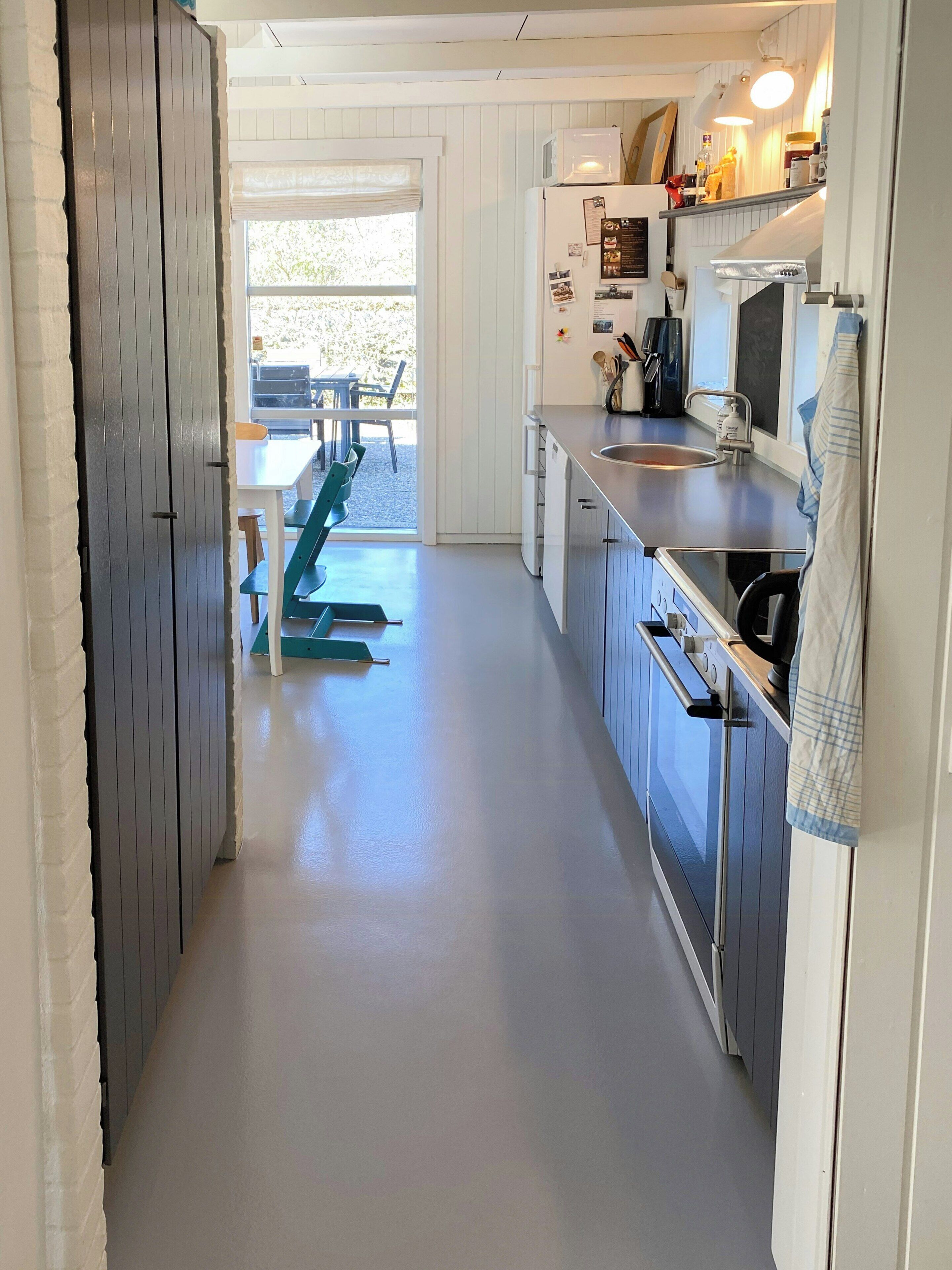 Una cucina ristretta con un'area pranzo visibile tramite una porta scorrevole, un frigorifero, un forno a microonde e un lavandino.