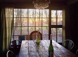 Ein Holzespeisesaal mit Stühlen, einer Chandelier und Blick auf Bäume durch große Fenster.