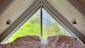 A room with a triangular ceiling and a large window. - Colorful summerhouse close to the sea (Maribo)