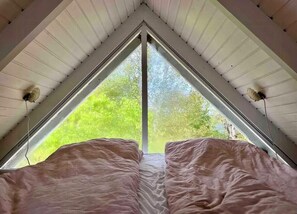 Ein Zimmer mit triangularer Decke und einem großen Fenster.