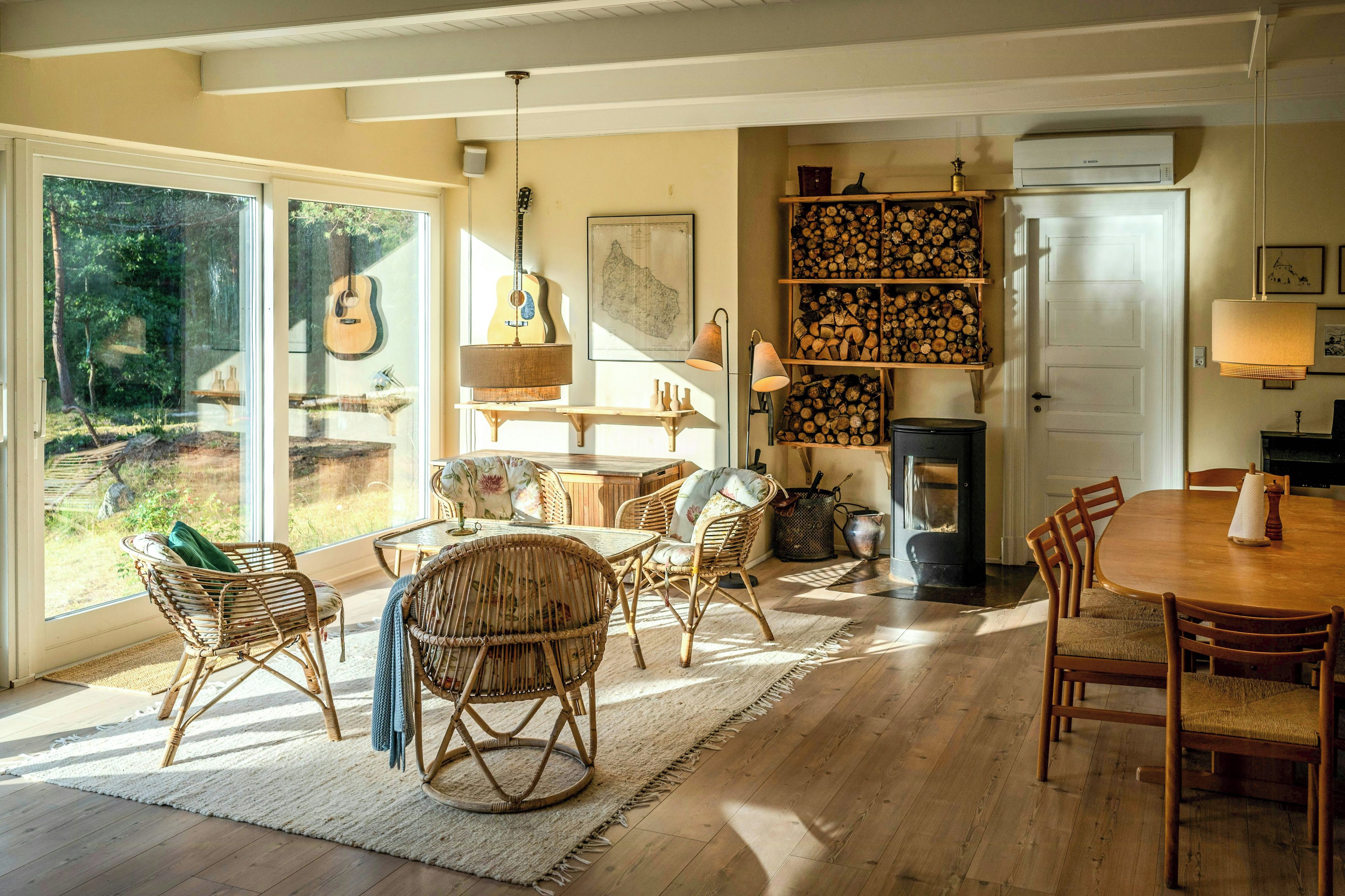 A cozy interior with wicker furniture, a fireplace, and a view through large windows.