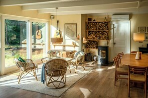 A cozy interior with wicker furniture, a fireplace, and a view through large windows. - Red stone house by Dueodde Beach (Nexø)
