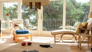 A spacious balcony with wicker furniture, a wooden table, and a remote control on the floor. - Red stone house by Dueodde Beach (Nexø)