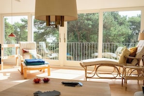 Een ruim balkon met rieten meubels, een houten tafel en een afstandsbediening op de vloer.