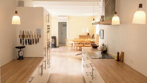 A modern kitchen with wooden countertops, a dining area with a table and chairs, and pendant lighting. - Red stone house by Dueodde Beach (Nexø)