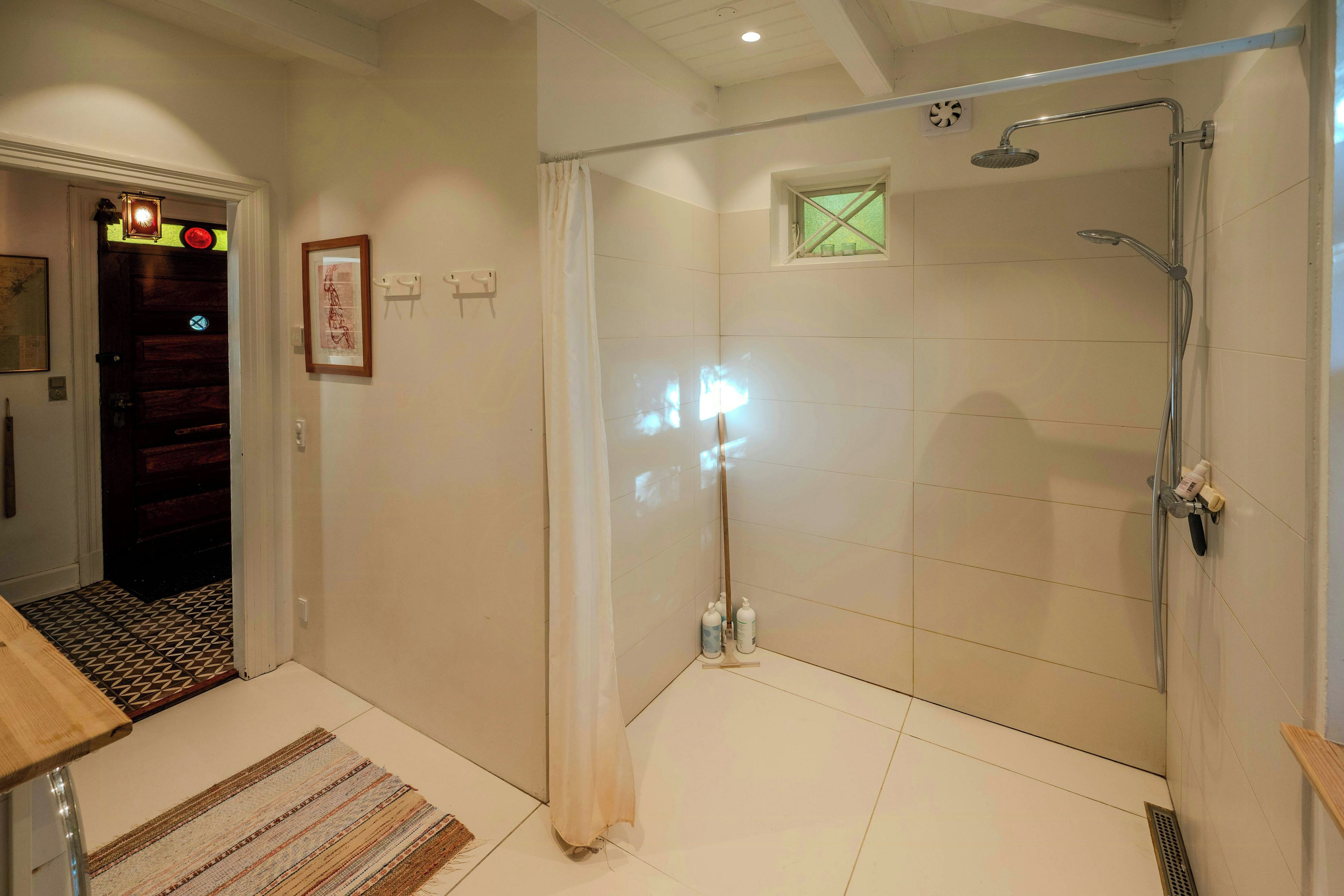 Un baño con cabina de ducha de vidrio, suelo de baldosas y puerta de madera.