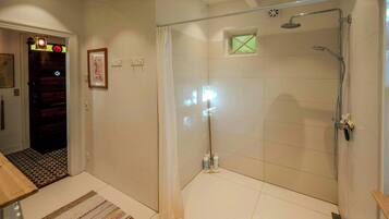 Un baño con cabina de ducha de vidrio, suelo de baldosas y puerta de madera.