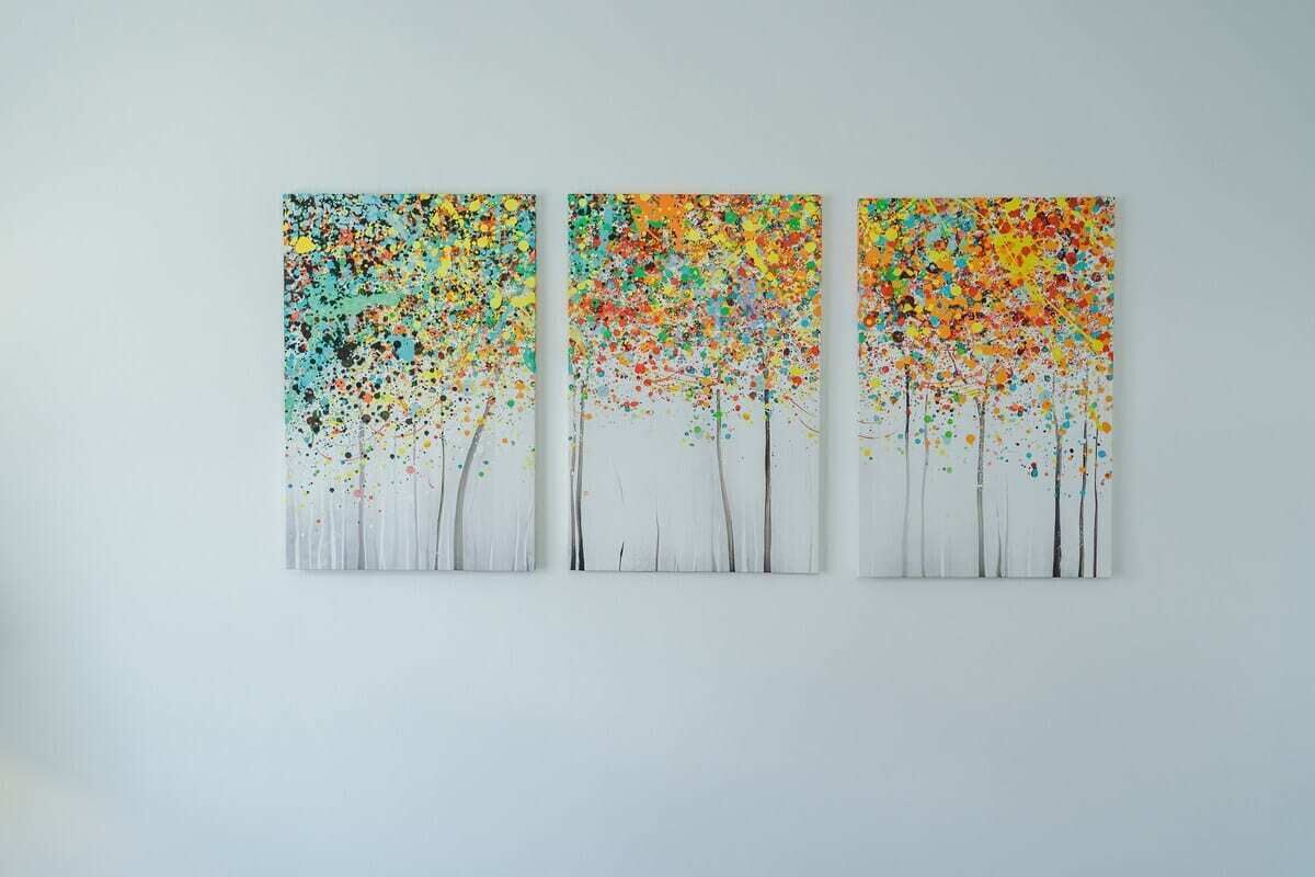 A wall with three abstract paintings of trees.