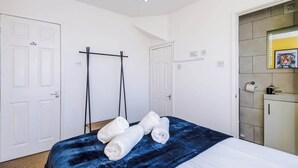 Ein Schlafzimmer mit Bett, Handtuchhalter, Kleiderschrank und Tür.