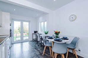 A modern kitchen with a dining area, large windows, and a clock on the wall. - Spacious 4BR Sleeps 7 | Contractor Stays (Hawarden)