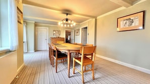 A dining room with a wooden table and chairs, a chandelier, and framed artwork on the walls.