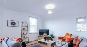 A living room with a sofa, armchair, TV, and shelves. - Comfortable 3BR Sleeps 6 | Contractor Stays (Hawarden)