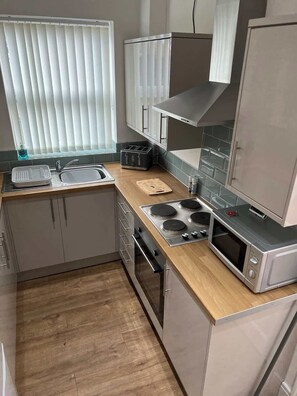 A compact kitchen with a sink, toaster, stove, oven, and microwave. - Comfortable 3BR Sleeps 7 | Contractor Stays (Ewloe)