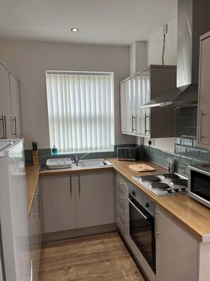 A modern kitchen with a built-in oven, a stovetop, and a sink. - Comfortable 3BR Sleeps 7 | Contractor Stays (Ewloe)