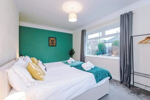 A hotel room with a bed, a window, a coat rack, and a green wall. - Comfortable 3BR Sleeps 6 | Contractor Stays (Flintshire)