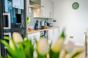 A modern kitchen with a microwave, toaster, and hanging utensils. - Comfortable 3BR Sleeps 6 | Contractor Stays (Flintshire)