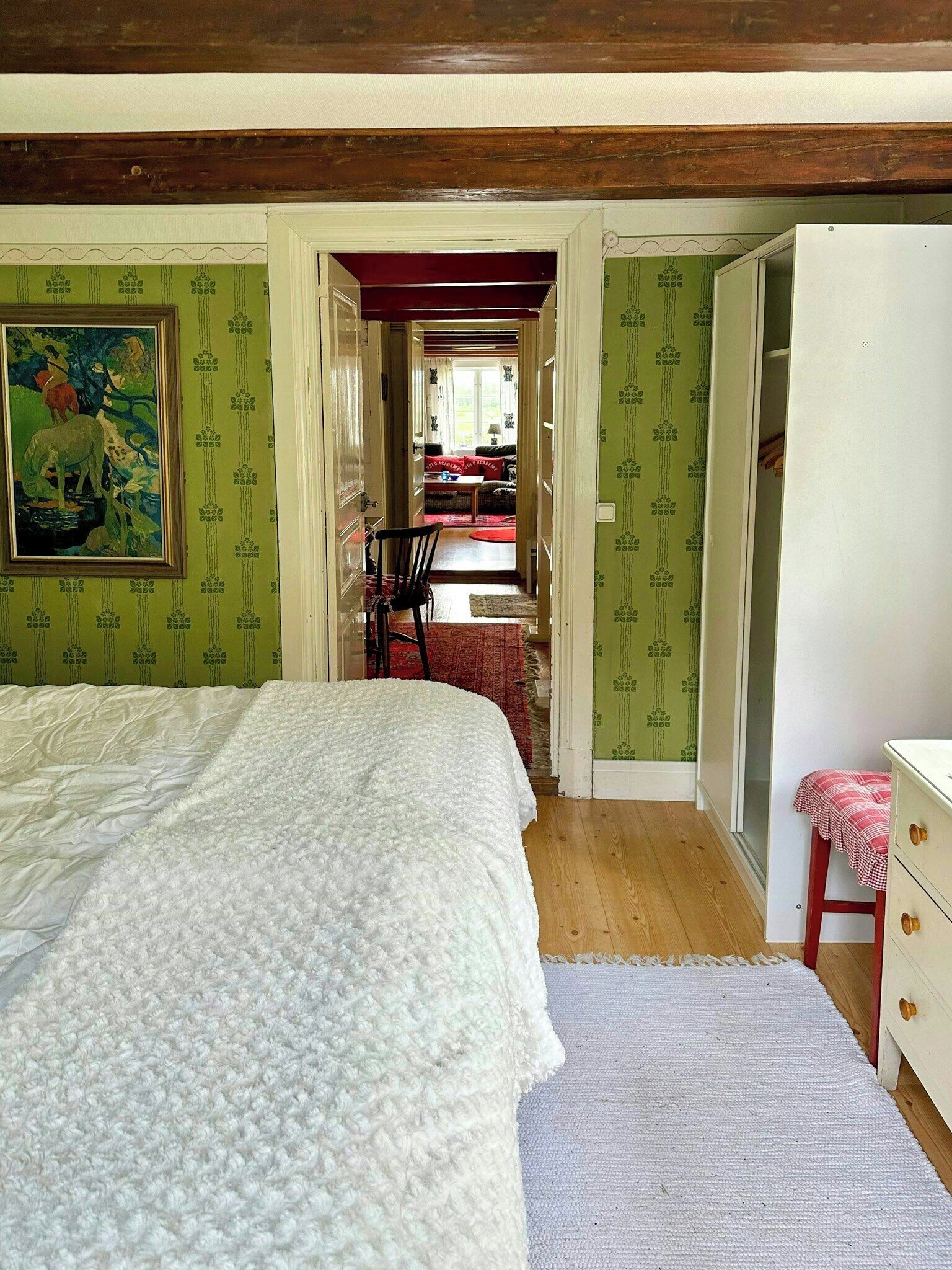 Een slaapkamer met een bed, een stoel, een tafeltje en een kledingkast.