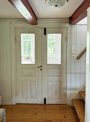 A white door with two windows, a wooden floor, and a staircase to the right.