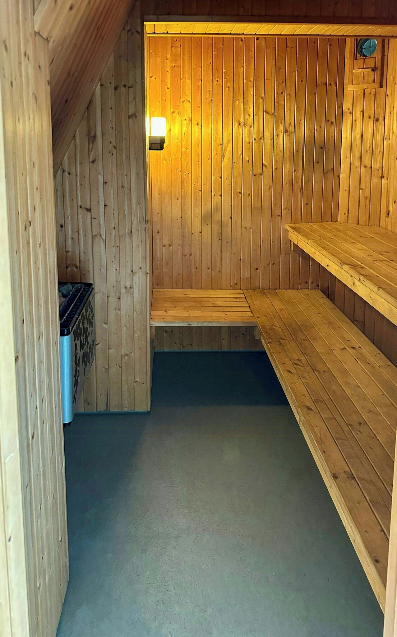 Ein Saunaraum mit Holzwänden, einer Sitzbank und einer Leuchte.