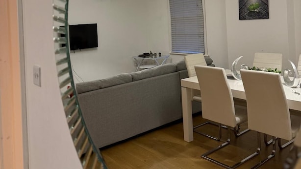 Ein modernes Interieur mit Essbereich, einer Couch, einem Fernseher und einem Gemälde an der Wand.