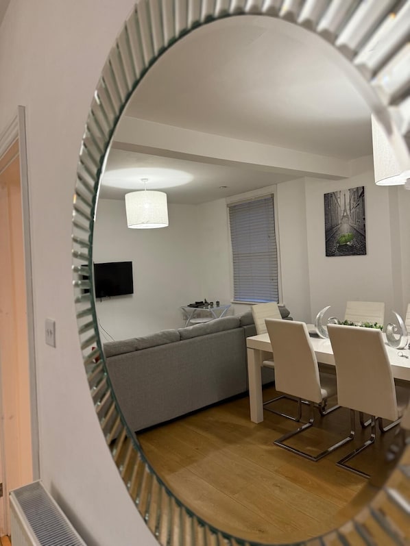 Ein modernes Interieur mit Essbereich, einer Couch, einem Fernseher und einem Gemälde an der Wand.