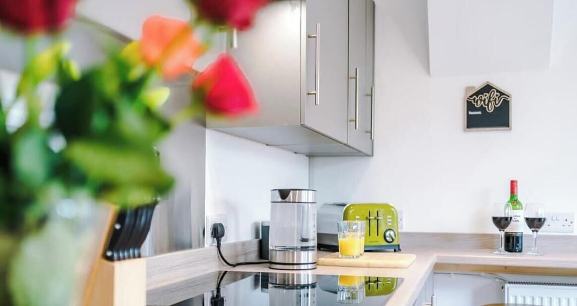 A modern kitchen with a coffee maker, toaster, and wine glasses on the counter.