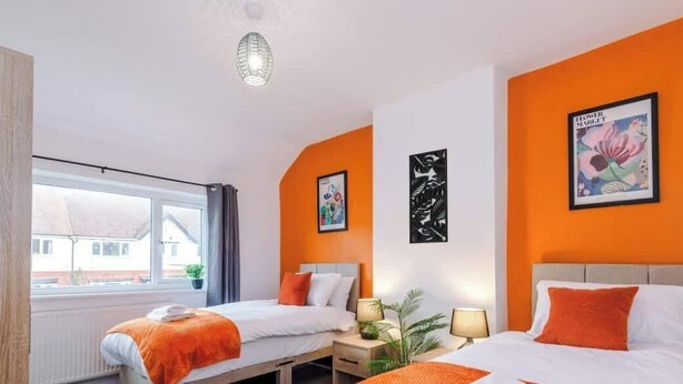 Et hotelværelse med to senge, et vindue og billedkunst på væggene.
