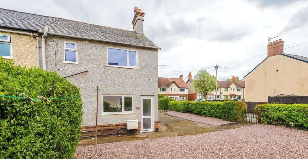 A residential house with a gravel driveway, a front door, and a visible window.