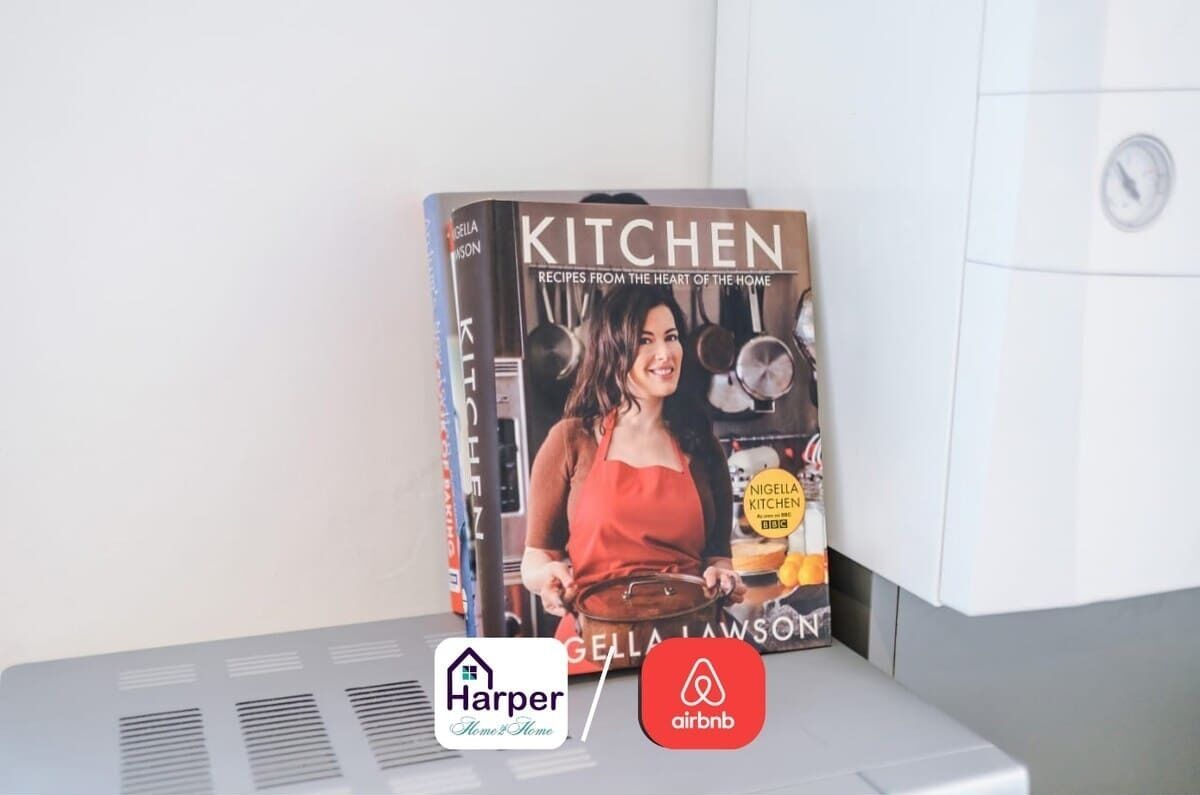 A cookbook titled 'KITCHEN' by Gella Lawson, placed on a white surface with a vent below.