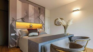 Un dormitorio moderno con una cama, una mesita de noche y dos sillas.