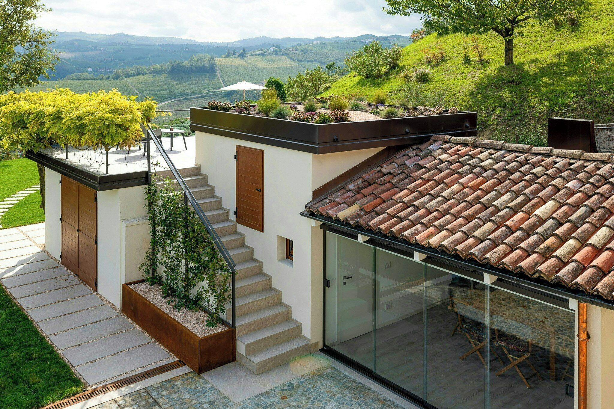 A modern house with a flat roof, a glass door, and a staircase leading to a deck.
